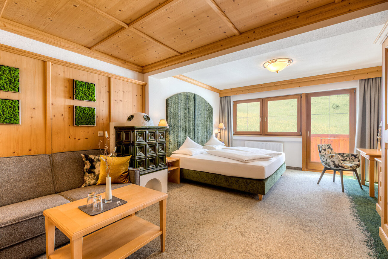 Ein gemütliches Zimmer mit Holzverkleidung, einem großen Bett und einer Sitzecke, die zum Entspannen einlädt.