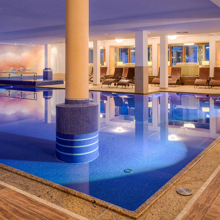 Der Innenbereich zeigt einen stilvollen Pool, der von Säulen und gemütlichen Liegen umgeben ist, ideal für Entspannung und Erholung.